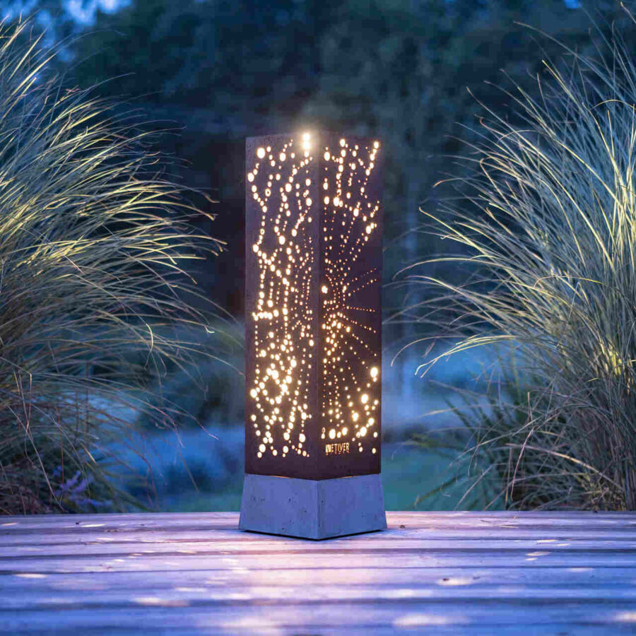 Lampa tarasowa rozświetlająca trawy ogrodowe, przestrzennym wzorem pajęczyny wypalonym na obudowie z blachy kortenowskiej.