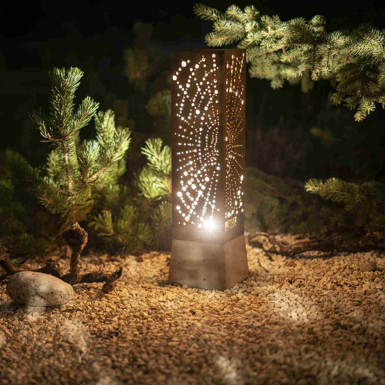 Wyjątkowa lampa ogrodowa z cortenu z wypalonym wzorem pajęczyny rozświetlająca nocą zakątek ogrodu.