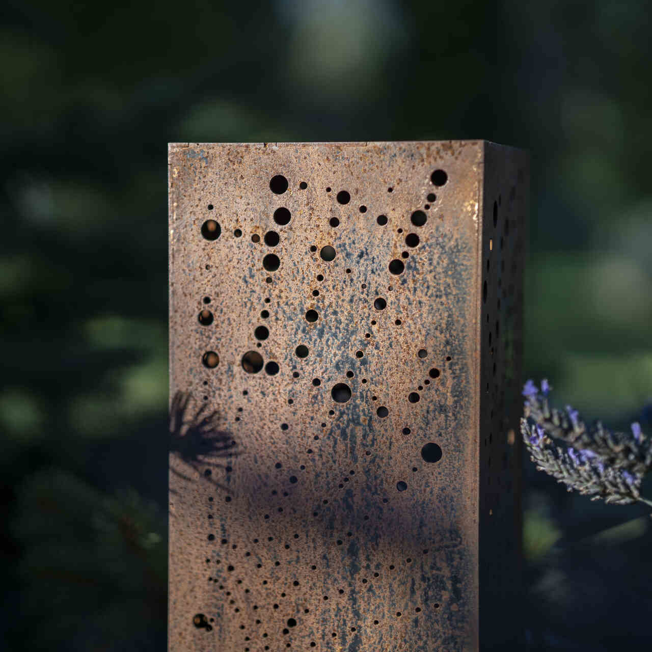 Fragment widoku lampy ogrodowej ze stali corten z wypalonym motywem pajęczyny.