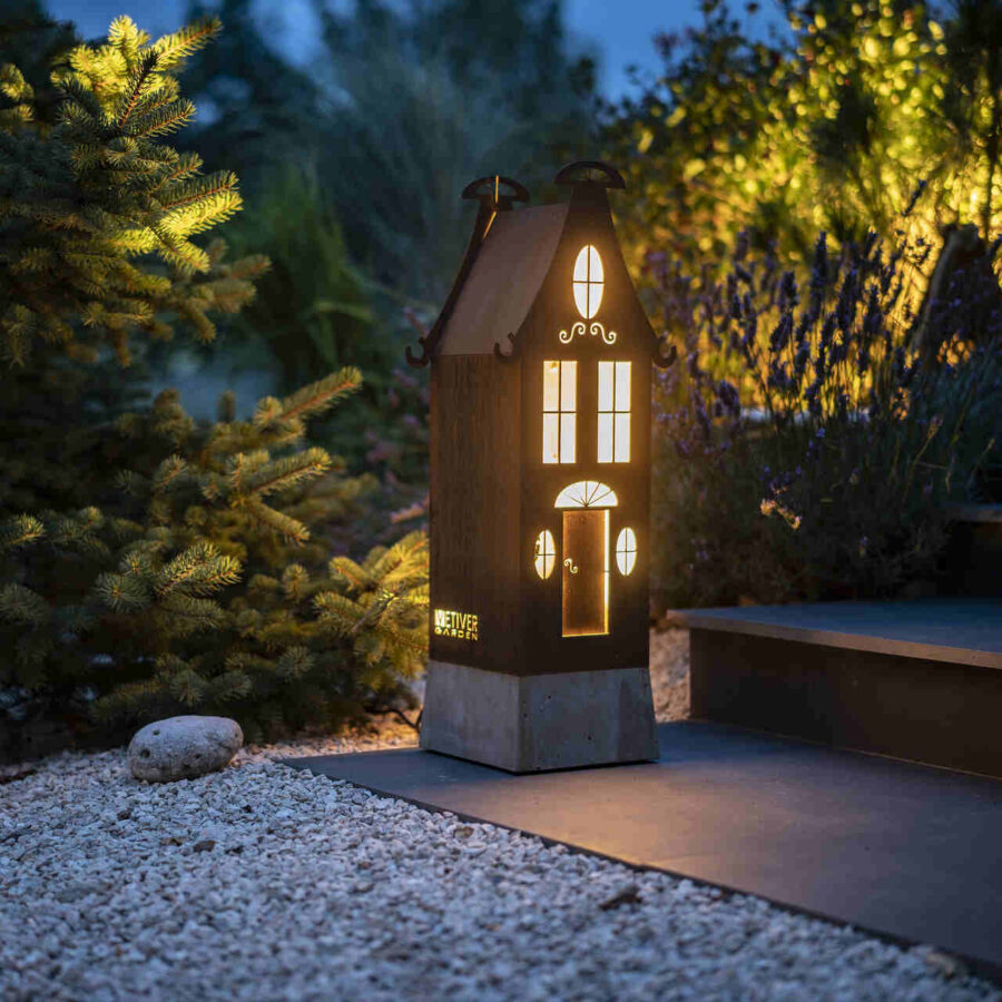Lampa zewnętrzna w kształcie domku rozświetlająca otoczenie domu i ogrodu.